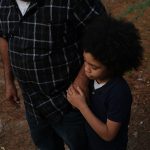 A father holds his son's hand outside their home in Jackson, Mississippi.