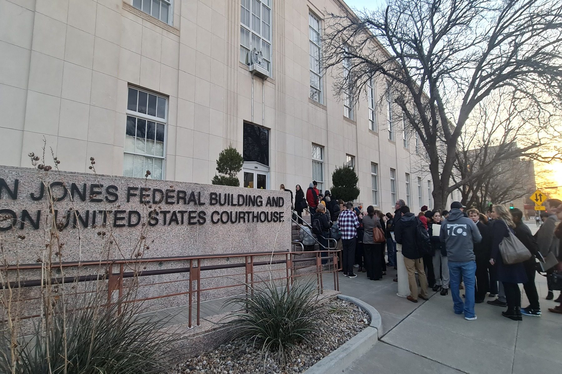 People stand outside of a courthouse.