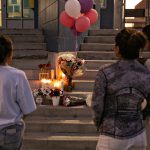 Students and community members pay their respects by placing flowers and candles on the steps of Helen Bernstein High School.