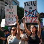 Protesters march while holding signs during an abortion-rights rally in Austin, Texas. The signs read 