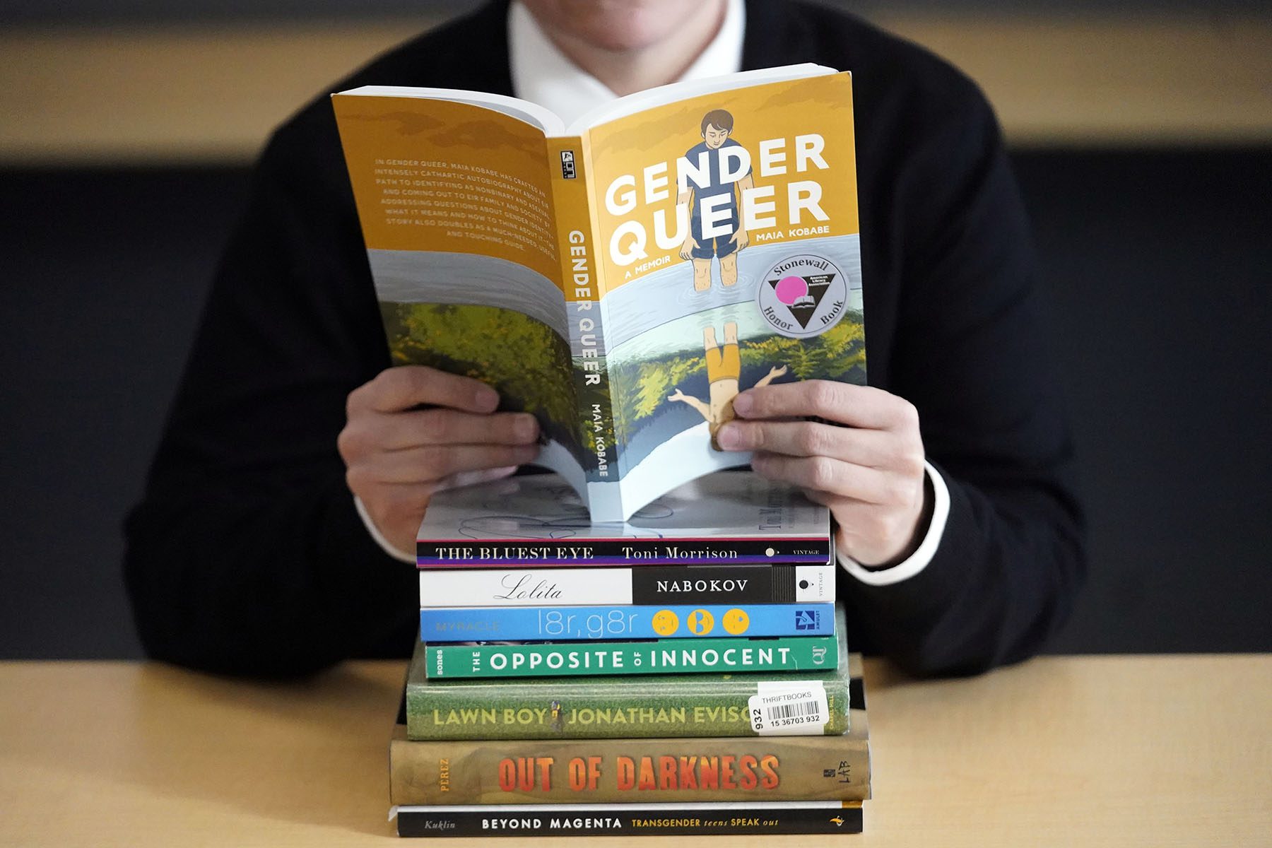 Student sitting behind a stack of books.