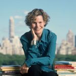 Judy Blume poses for a portrait in New York City in 2006. She is surrounded by books she's written. Behind her, the New York City skyline is seen.