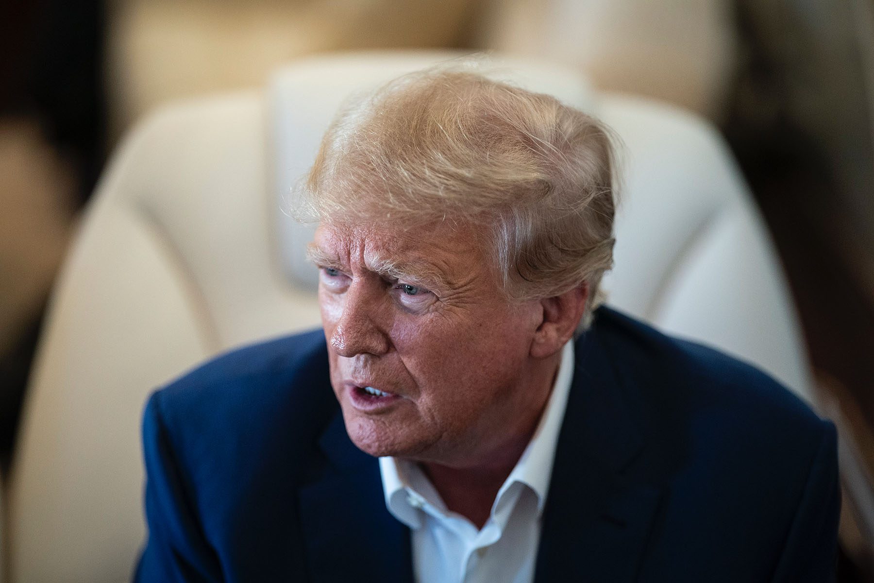 Former President Donald Trump speaks with reporters on his airplane while en route to Iowa.