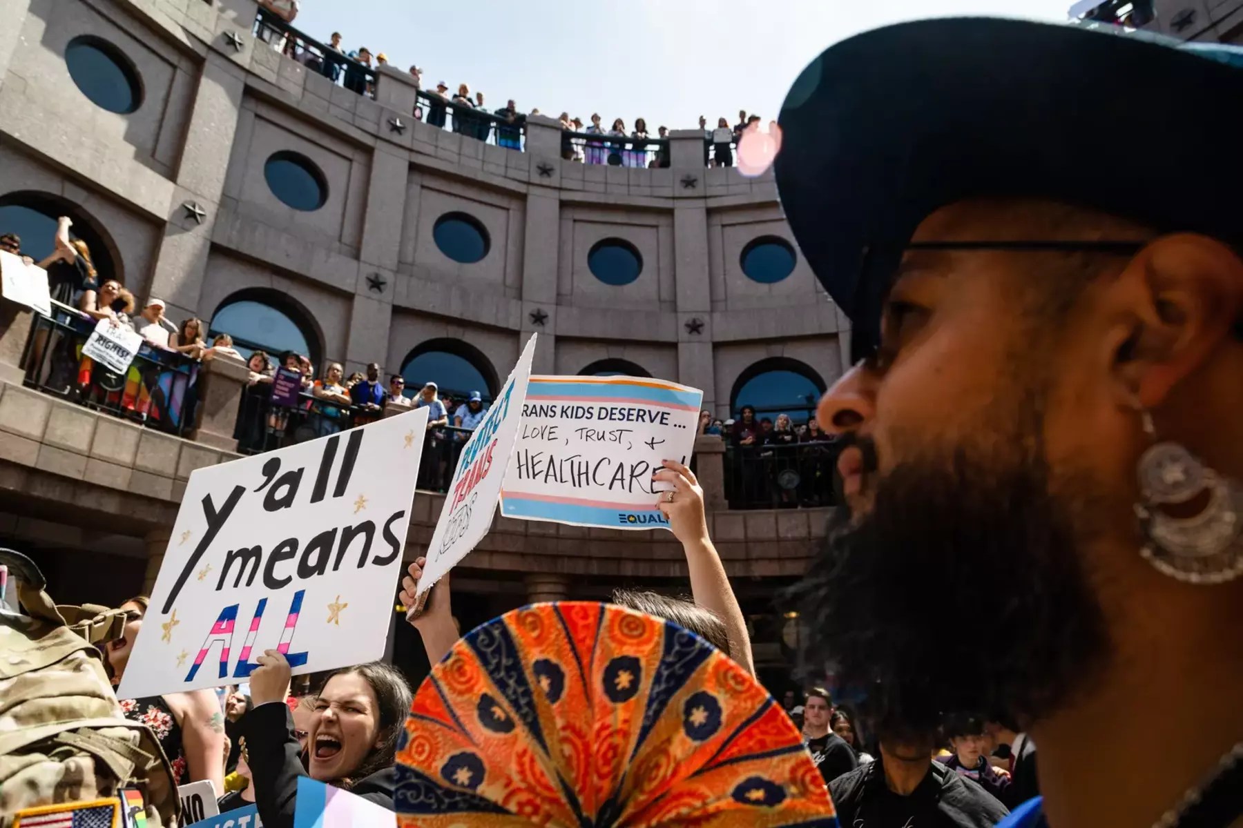 People protest with signs on the outdoor rotunda of the Texas Capitol in Austin.