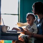 Woman working from home while holding toddler.