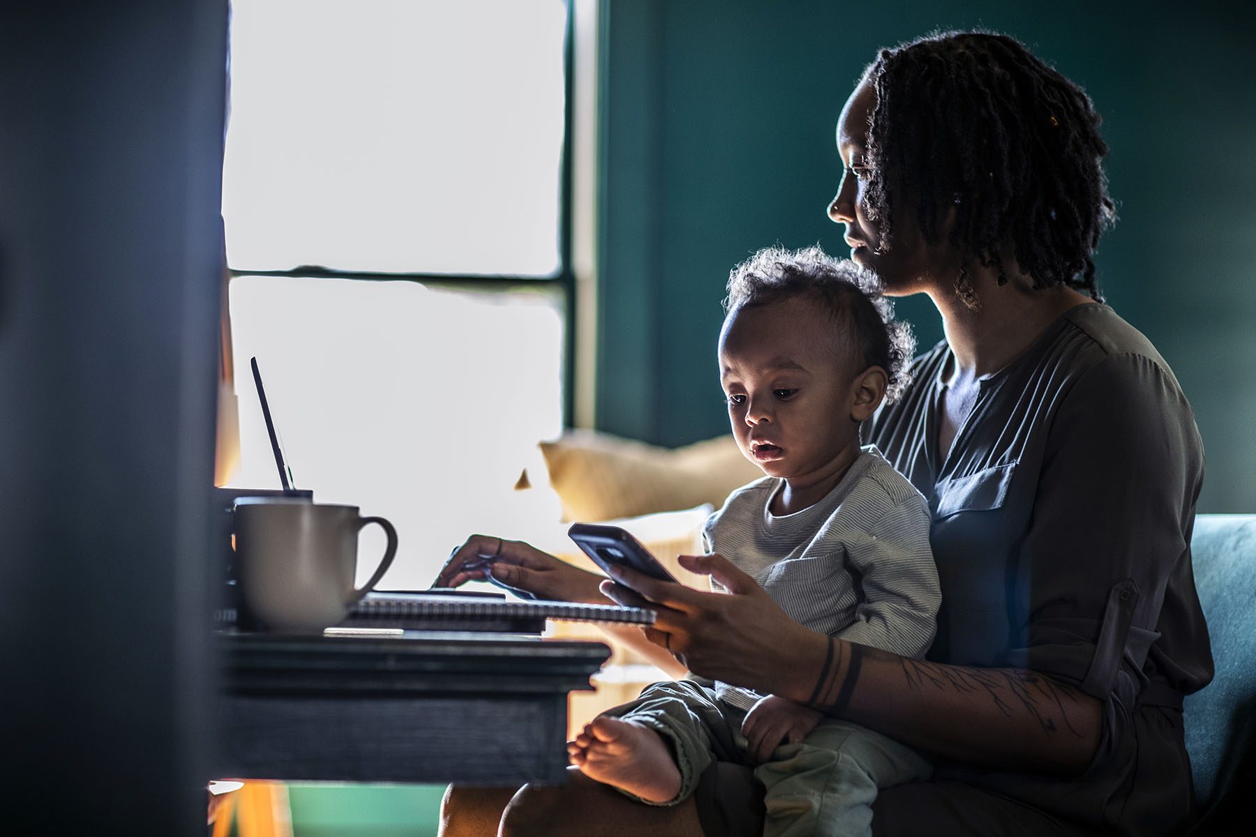 Woman working from home while holding toddler.