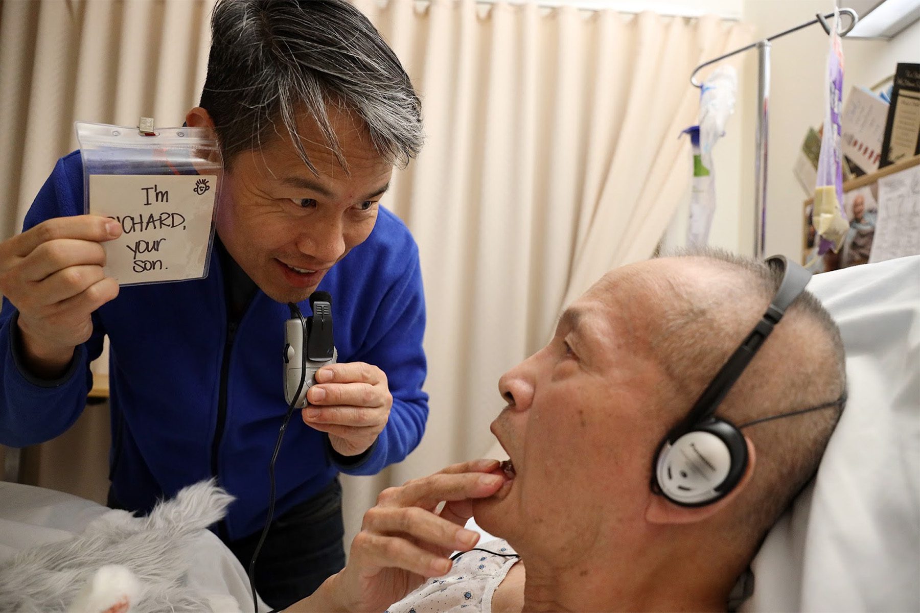 Richard Lui and his father, who has diagnosed with Altzheimer's 8 years ago. Richard Lui holds a note that reads "I'm RICHARD, you son" while his father lies in a hospital bed.