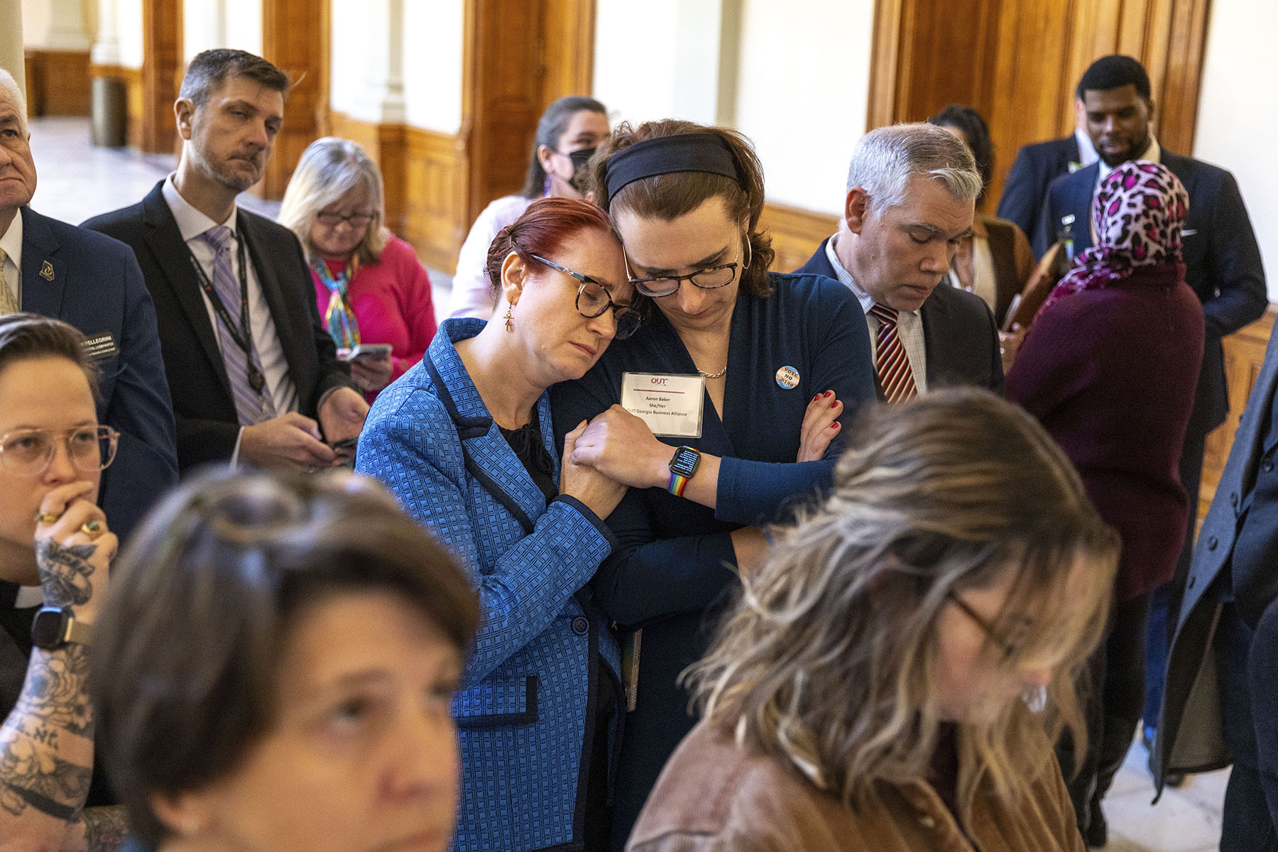 People lean on each other and hold hands while watching discussion of SB 140 at the Georgia State Capitol.