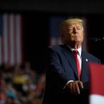 Donald Trump stands at a podium with American flags behind him