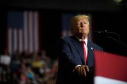 Donald Trump stands at a podium with American flags behind him