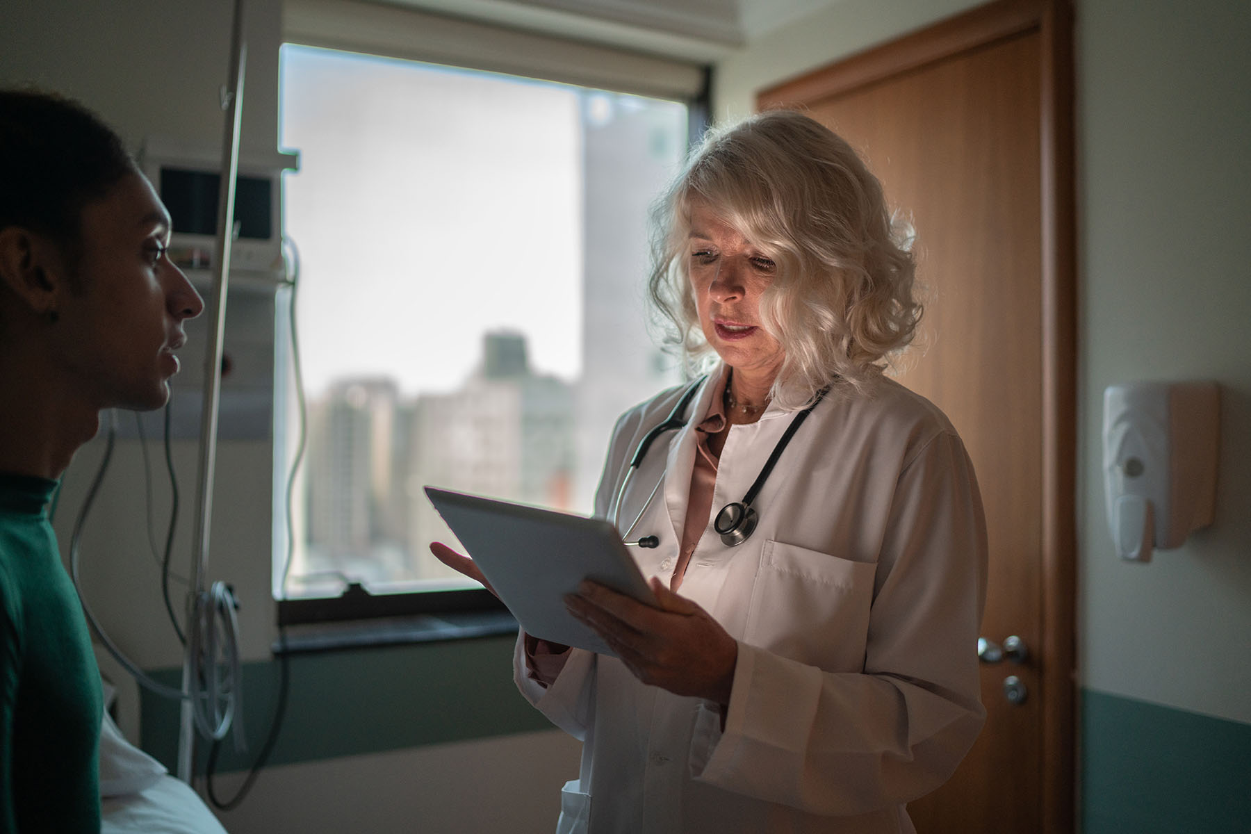 A doctor talks to a transgender patient in a hospital room.