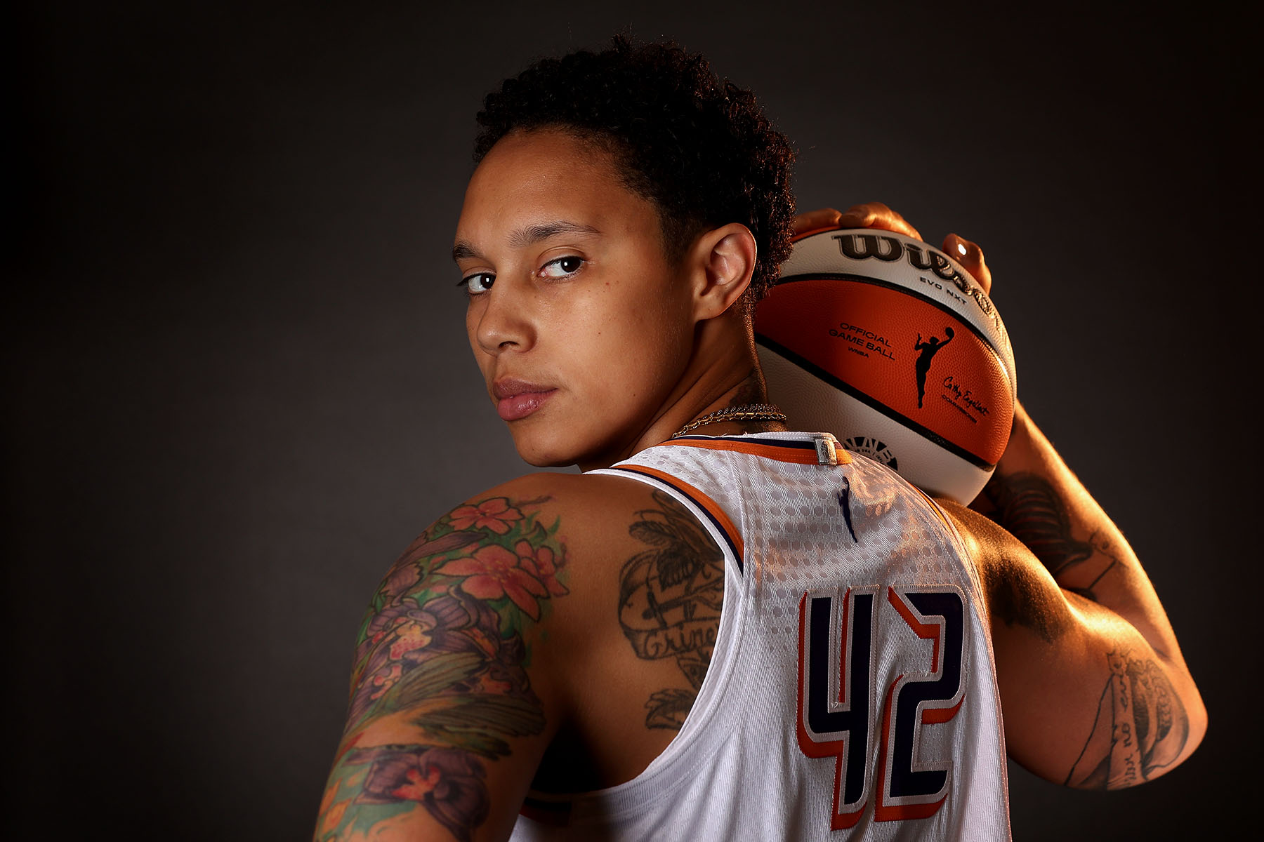 Brittney Griner looks back at the camera while holding a basketball as she poses for a portrait.