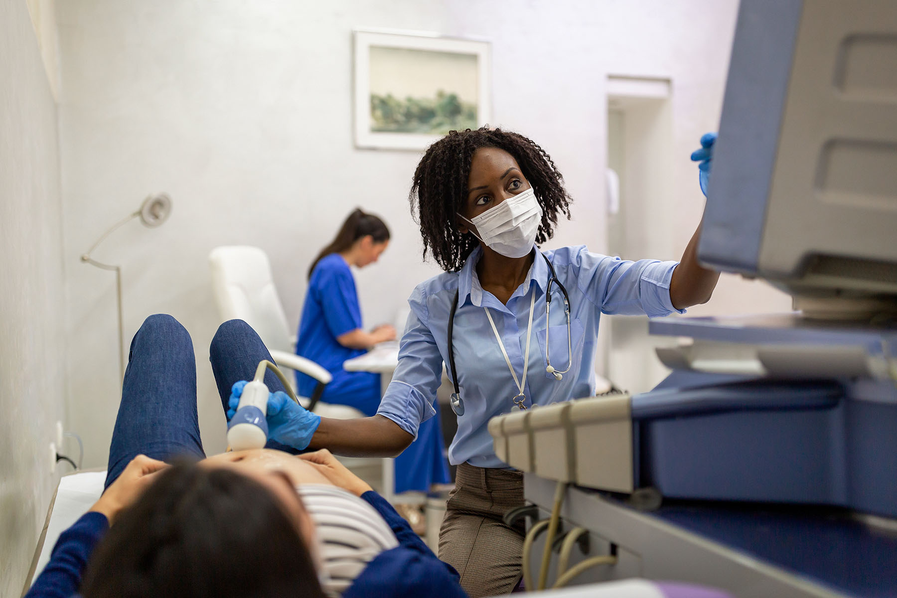 A female OBGYN doing ultrasound examination of a pregnant woman.