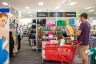 A customer with a child in their cart shops through Pride Month accessories at a Target store.