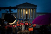 People rally in the rain to show support for the Biden administration's student debt relief plan in front of the Supreme Court.