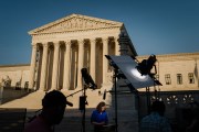 A news crew stands outside of the United States Supreme Court.