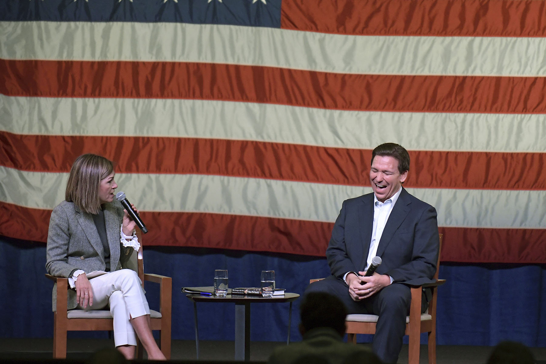 Gov. Ron DeSantis has a conversation with Iowa Gov. Kim Reynolds at an event.