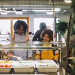 Friends choose their meal during lunch break in the cafeteria.