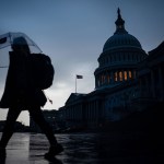 A pedestrian walks through the Capitol Plaza with the dome of the U.S. Capitol Building as a backdrop.