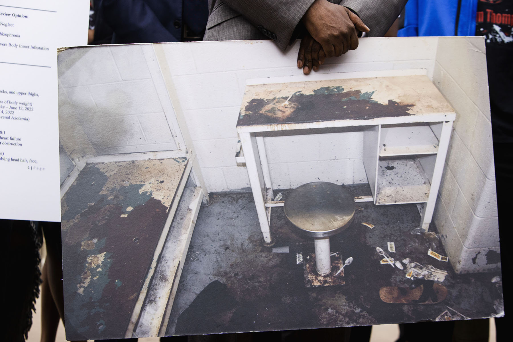 Attorney Michael Harper holds a photo of Lashawn Thompson's cell at the Fulton County Jail at a news conference. The cell is filthy, and filled with dirt and garbage. The furniture is rusted over and in terrible condition.