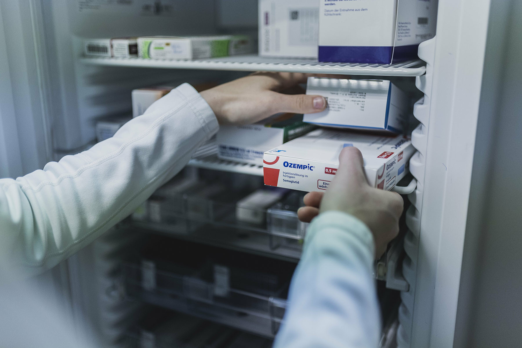 A pharmacists takes an Ozempic package out of a pharmacy fridge.