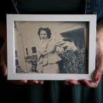 Hands hold a framed black and white photo of a woman smiling.