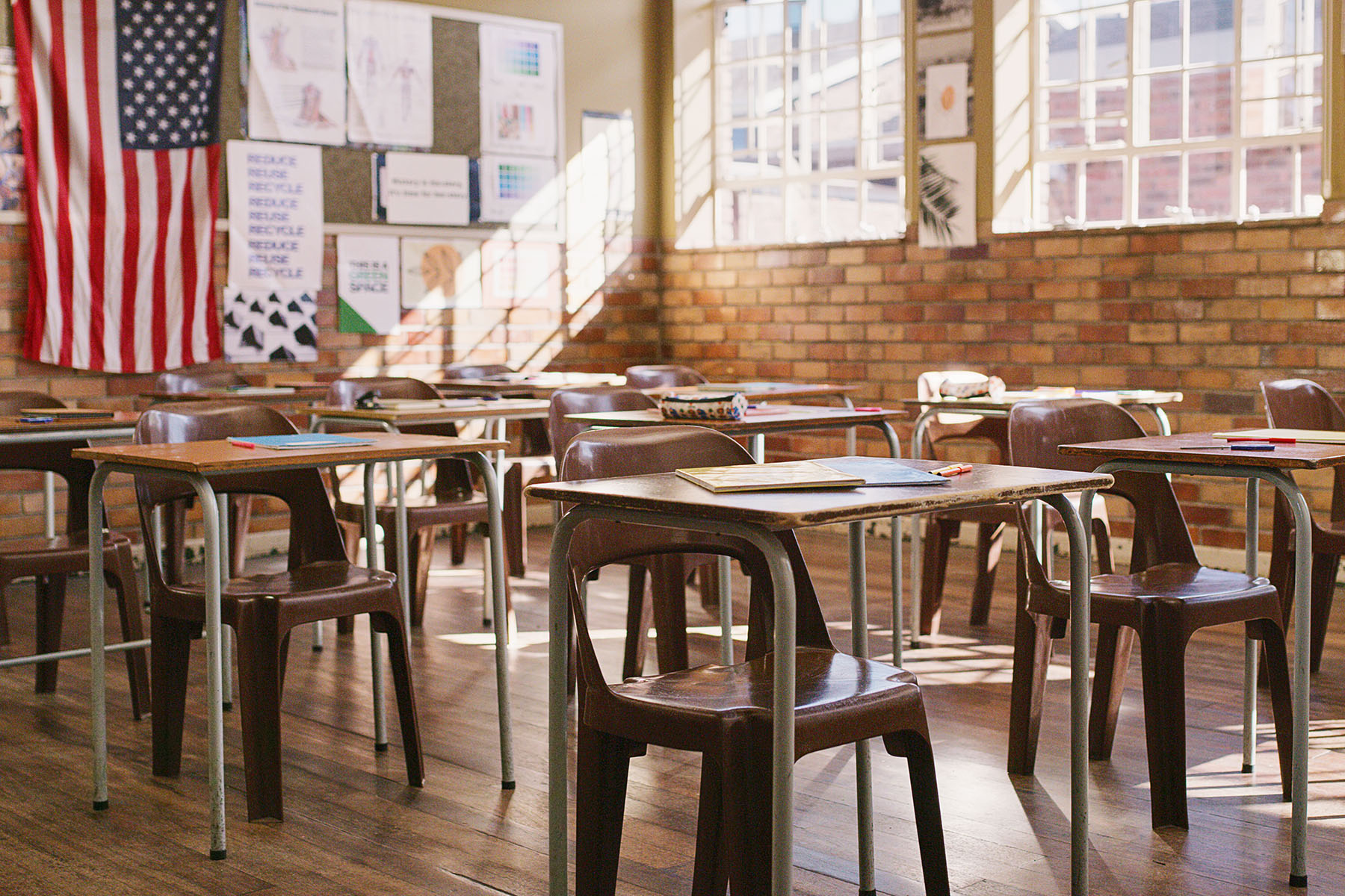 Empty classroom with wooden desks, table and chairs.