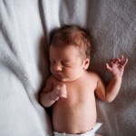 A close-up of a newborn baby lying on bed and sleeping.