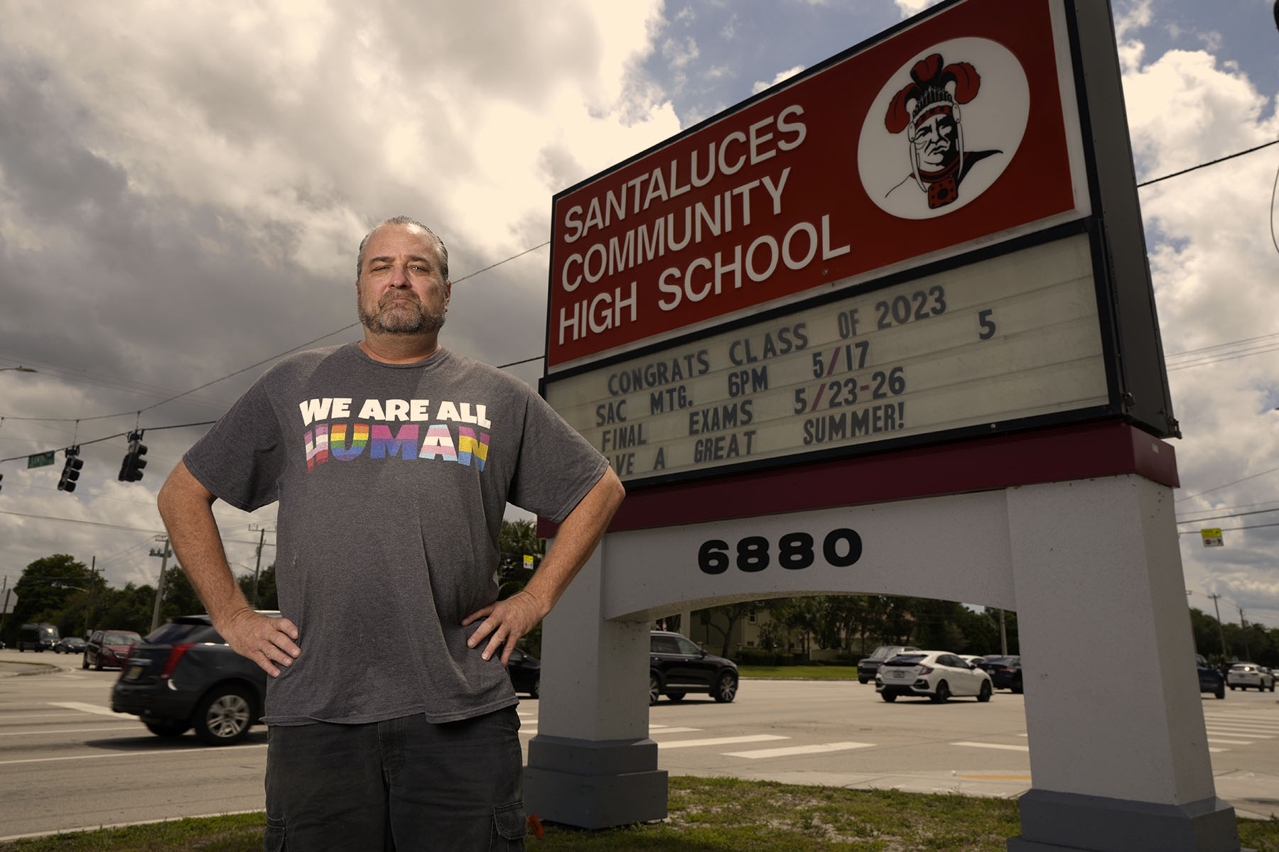 Michael Woods stands in front of his school sign in Lantana, Florida, wearing his protest shirt "We Are All Human."
