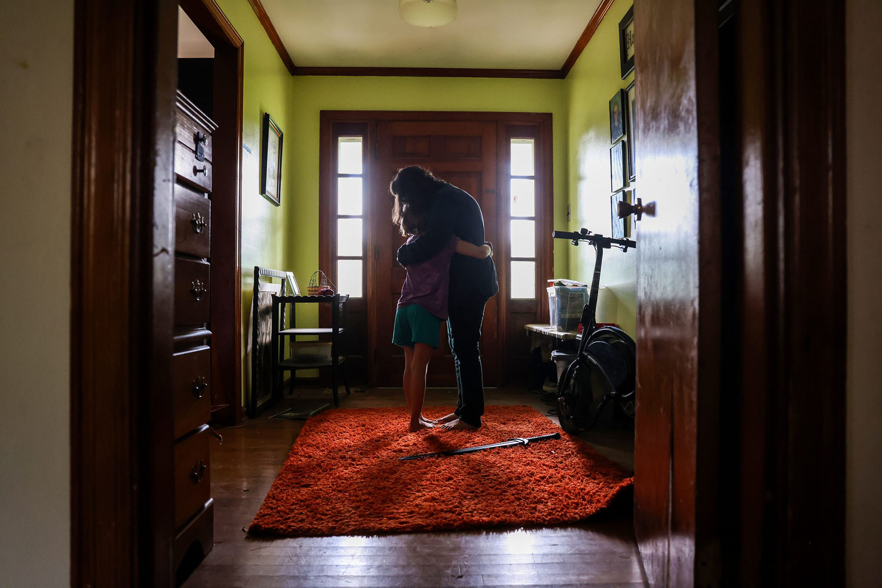 Marie gives one of her gender non-confirming children a hug in the doorway of their home.