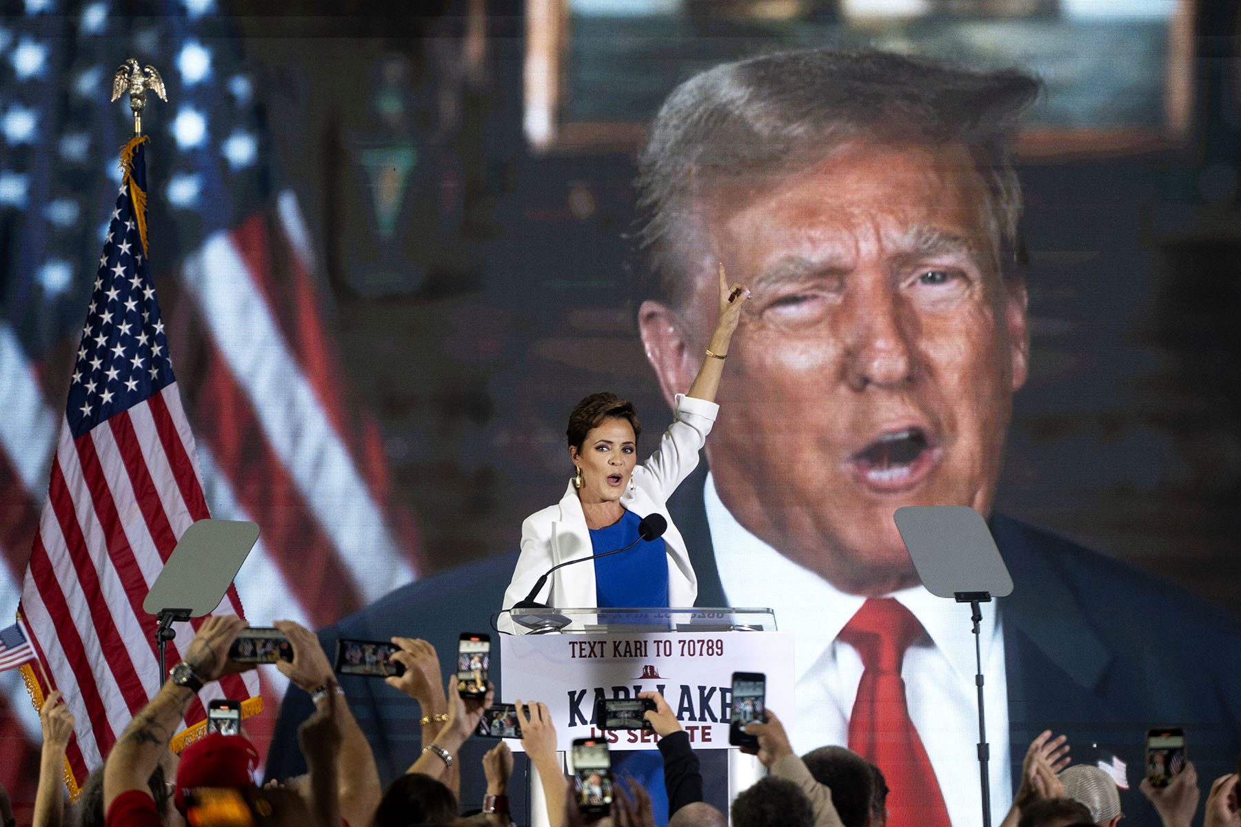 Kari Lake announces her bid for the seat of U.S. Sen. Kyrsten Sinema while a pre-recorded video of Donald Trump plays behind her.