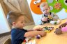 Two children play with wooden cars on table at daycare.