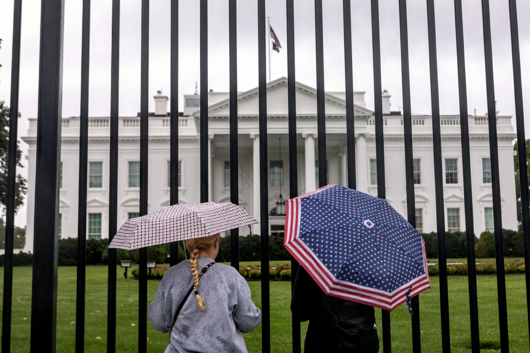 Tourists stand in front of the White House.