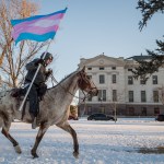 An indigenous protester rides across the South Dakota Capitol lawn on horseback.