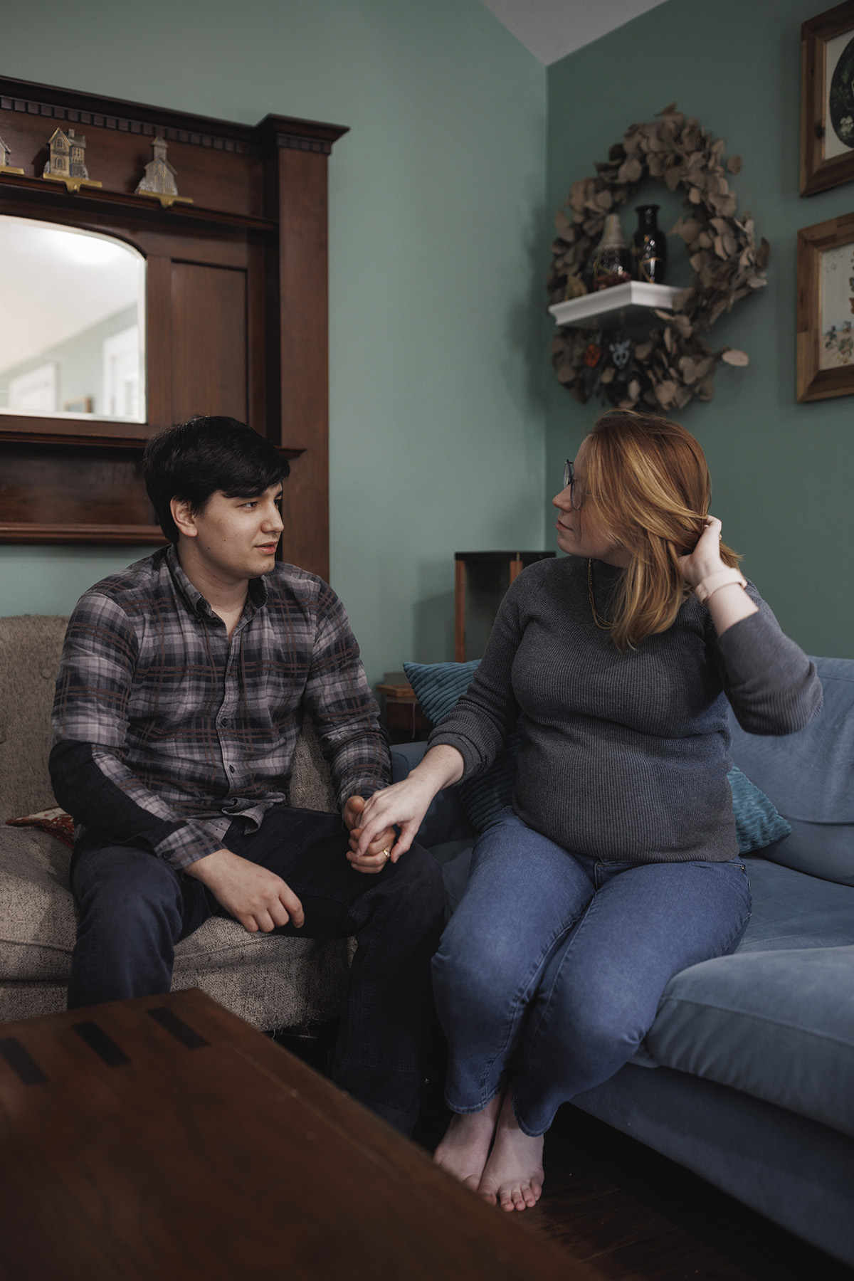 Carver and her partner hold hands on their couch.