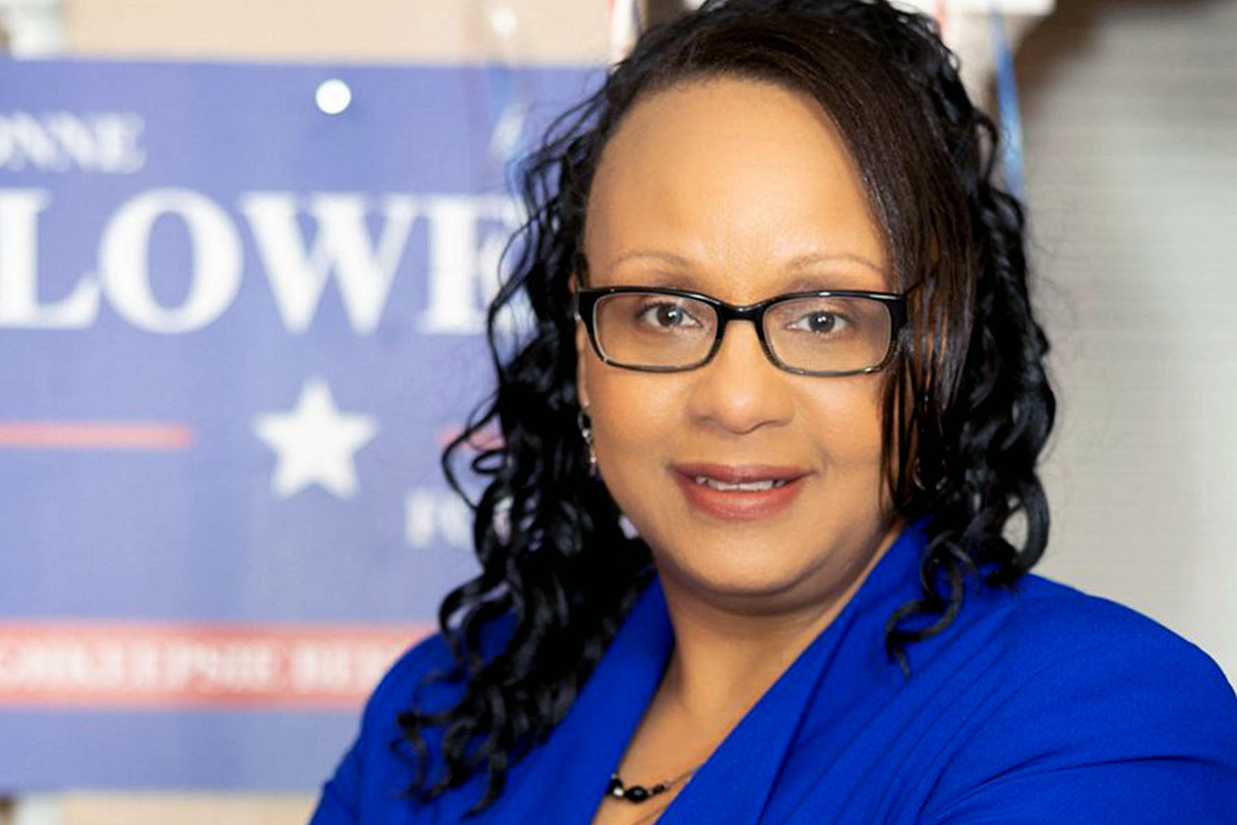 Yvonne Flowers smiles as she poses in front of a campaign sign.