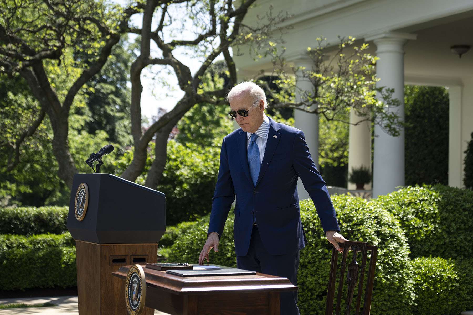 President Biden steps towards a table and chair as he prepares to sign an executive order in the Rose Garden of the White House.