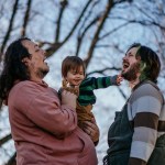 Joey Guido and Sam Guido laugh together as they hold their 16-month-old daughter in the backyard of their home.