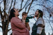 Joey Guido and Sam Guido laugh together as they hold their 16-month-old daughter in the backyard of their home.