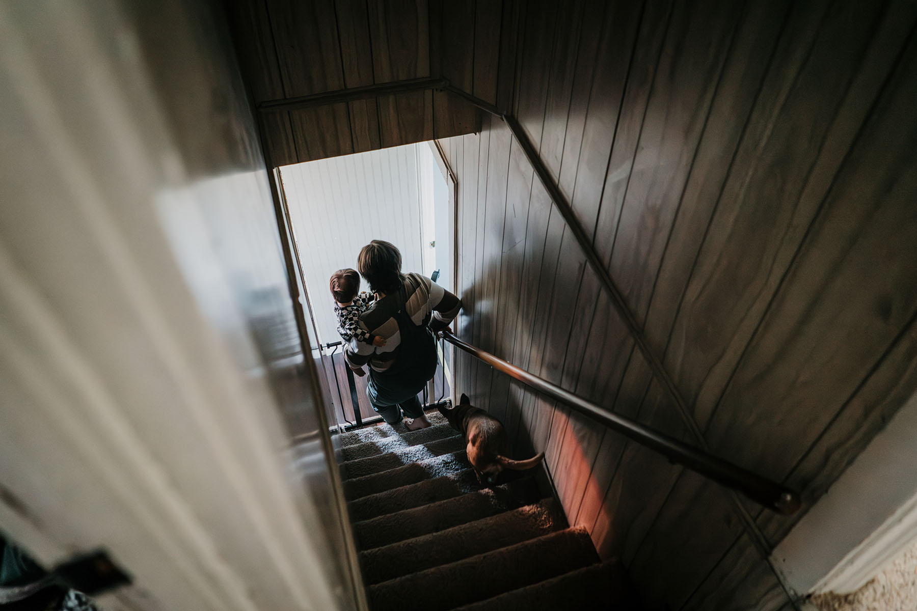 Sam Guido carries their 16-month-old daughter down the stairs after an afternoon nap.