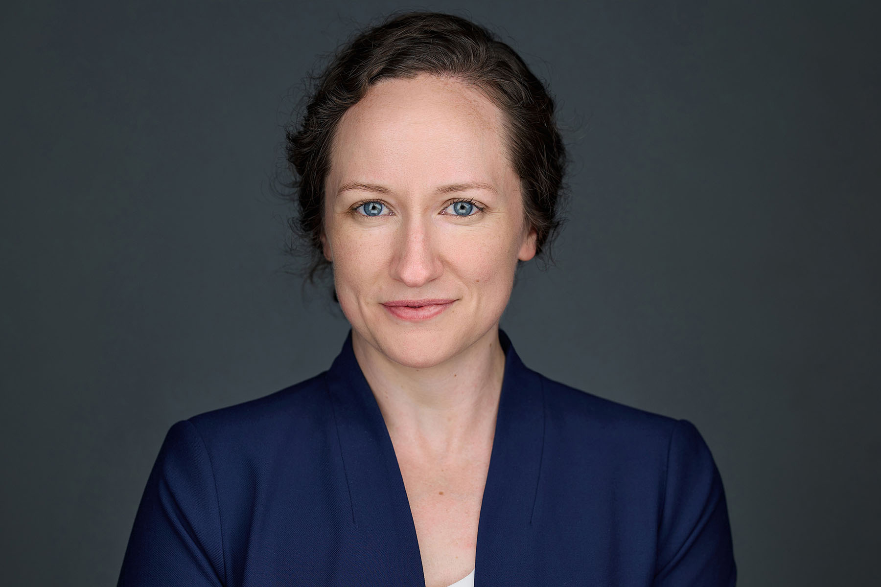 Emma Brown wears a blue jacket and smiles softly in this headshot.