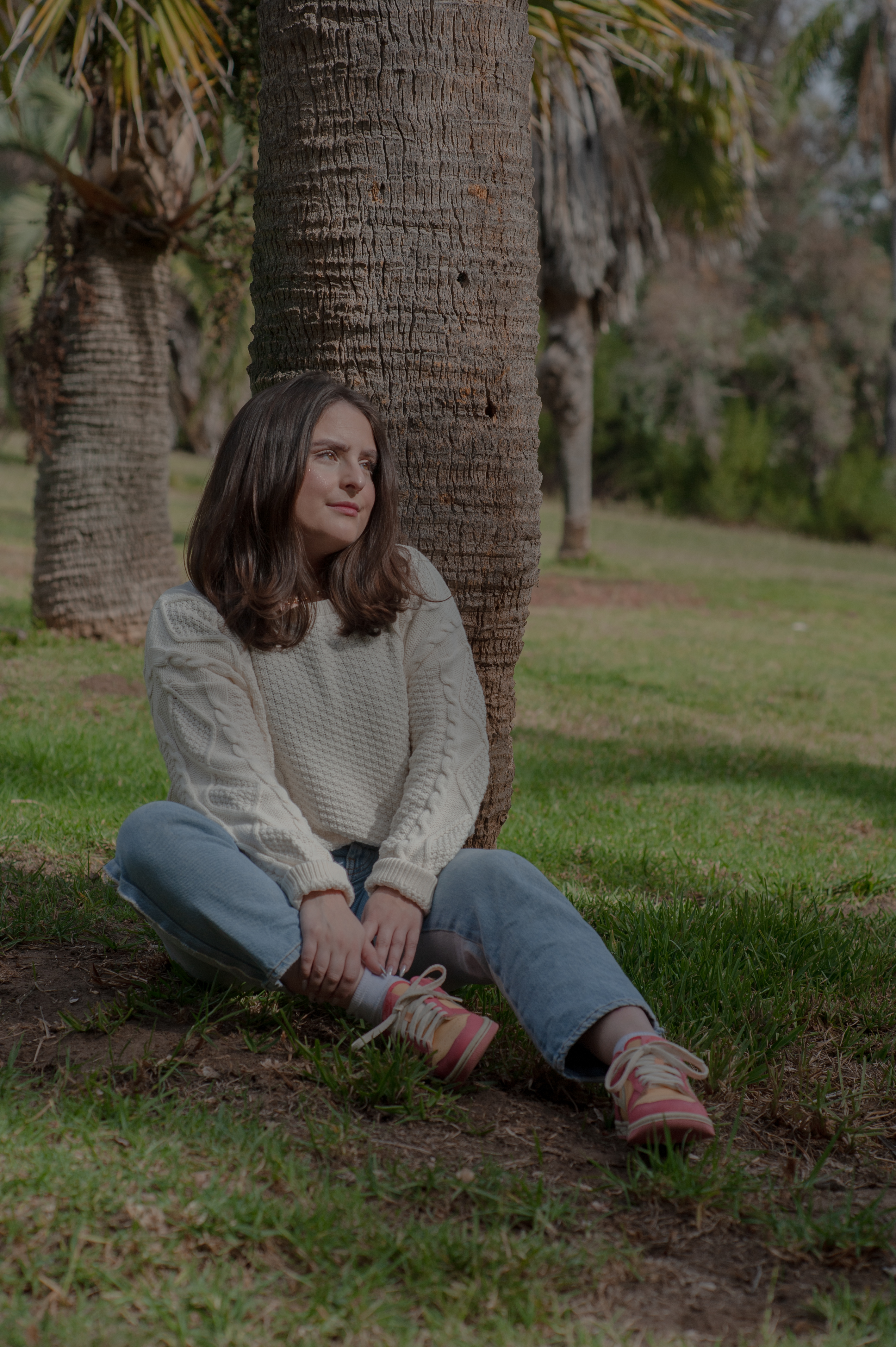 Amy Valencia leans against a palm tree as she poses for a portrait.