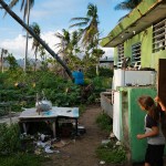 A child watches his father cut a fallen tree in the backyard of their home in the aftermath of Hurricane Maria.