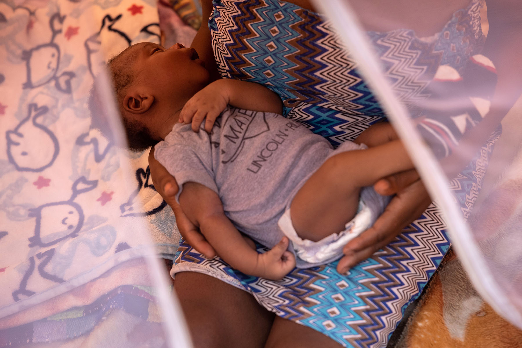 A mother holds her sleeping baby.