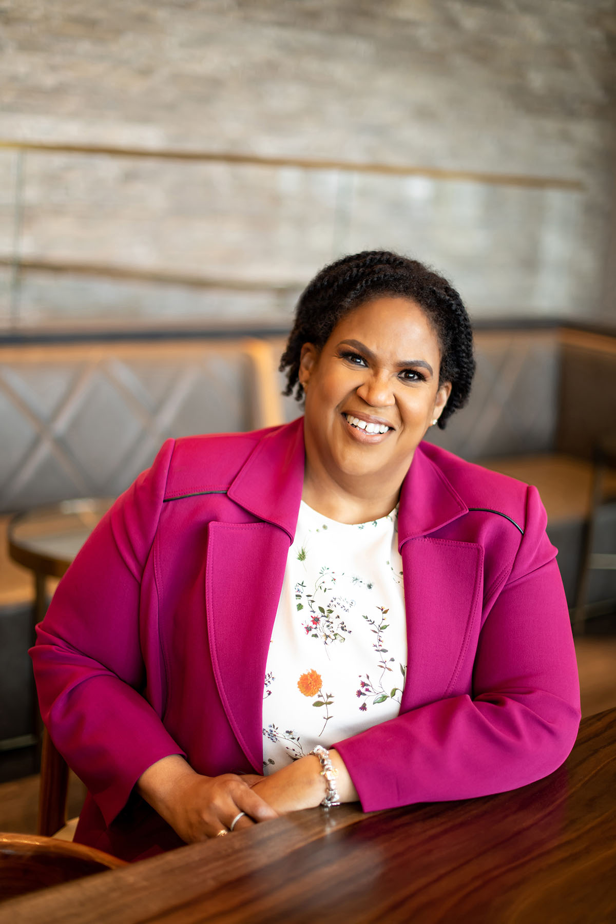 Portrait of Lavora Barnes smiling and sitting at a wooden table.