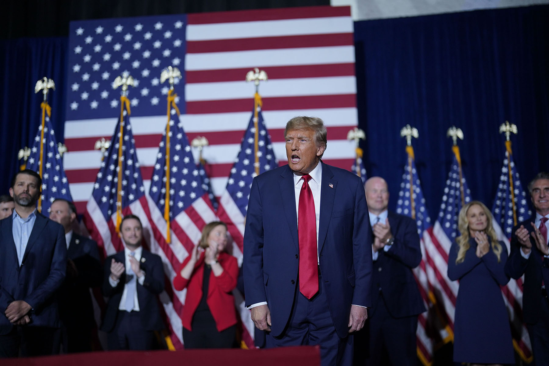 Donald Trump is seen on stage surrounded by America flags.