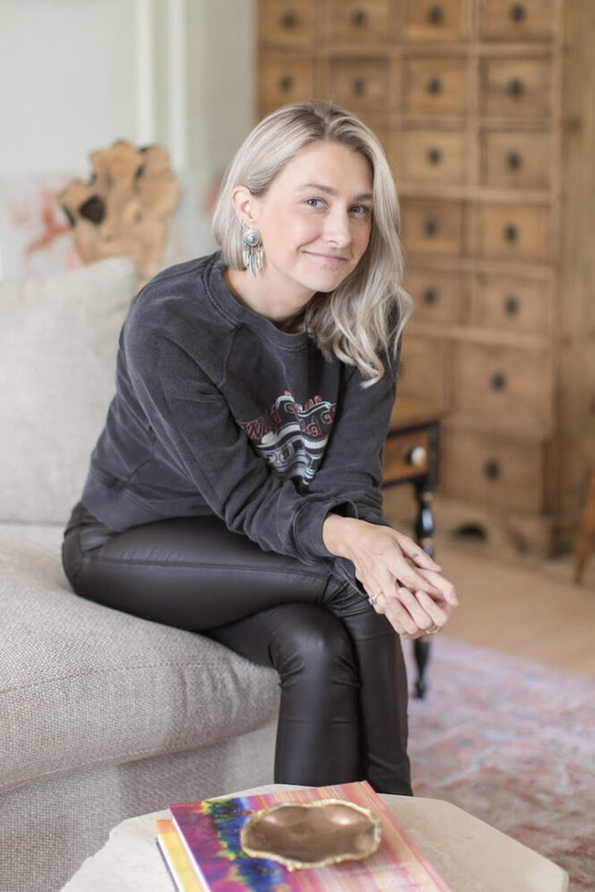 Portait of Jamie Corley sitting on a couch and smiling.