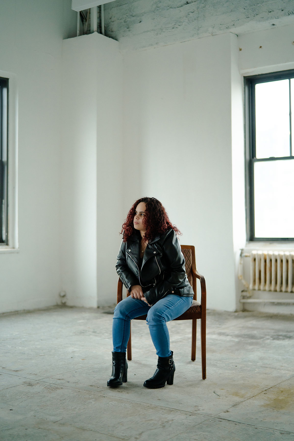 Thalia Gonzalez poses for a portrait while sitting on a chair in a empty room.