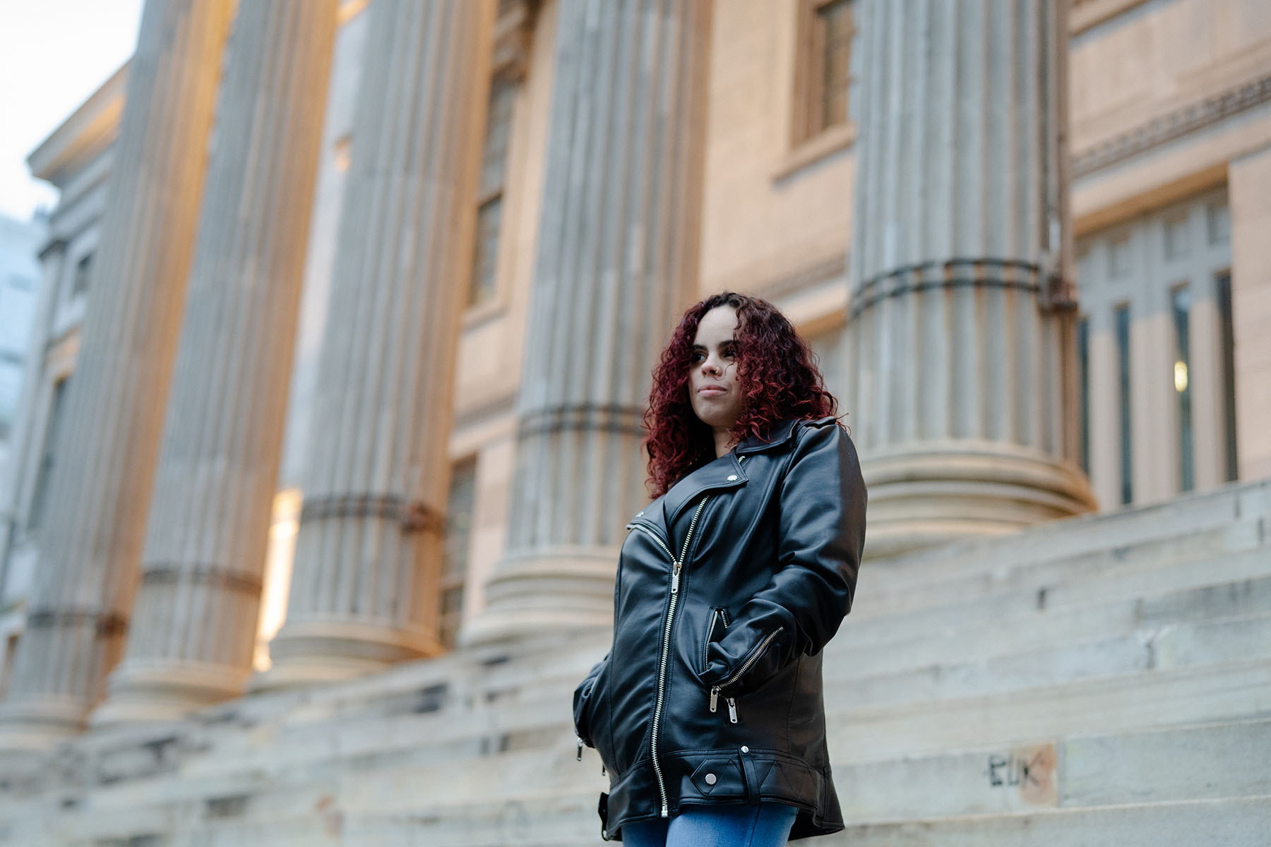 Thalia Gonzalez smiles faintly as she poses for a portrait on the steps of a judicial building in New York City.