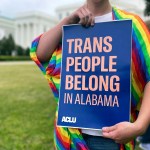 A person holds up a sign reading, 